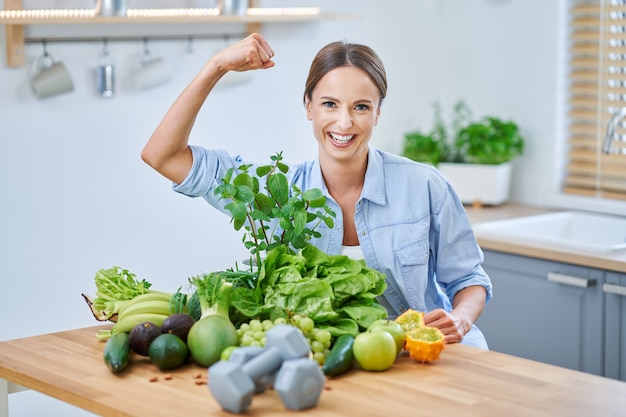 Mujer adulta sana con comida verde en la cocina