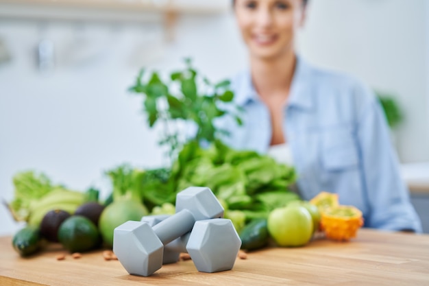 Mujer adulta sana con comida verde en la cocina