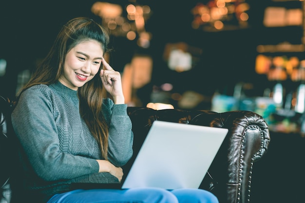 Una mujer adulta sonriente usando una computadora portátil en un café.