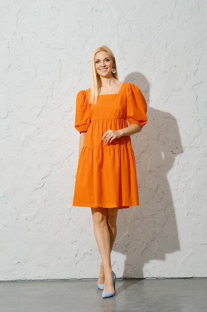Mujer adulta sonriente con vestido naranja caminando