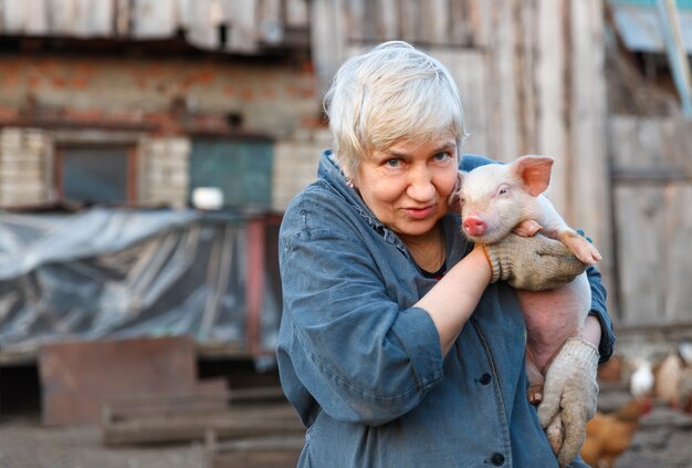 Mujer adulta sosteniendo un cerdo pequeño y mirando a la cámara