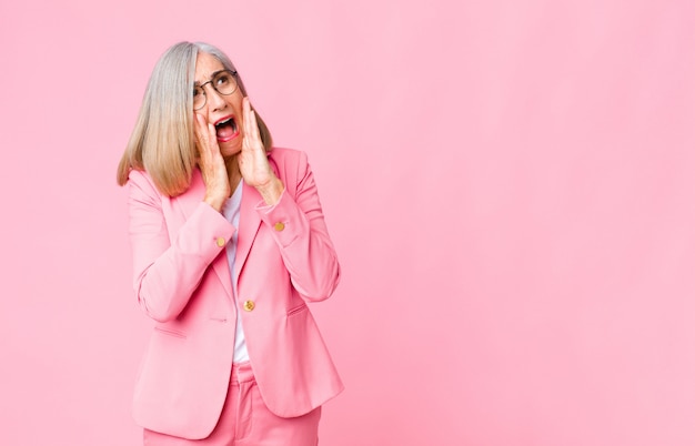 Mujer adulta en traje rosa sintiéndose emocionado y sorprendido mirando hacia un lado