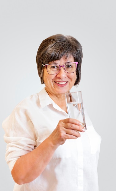 mujer adulta se para con un vaso de agua