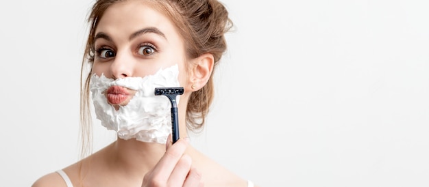 Mujer afeitarse la cara por la maquinilla de afeitar