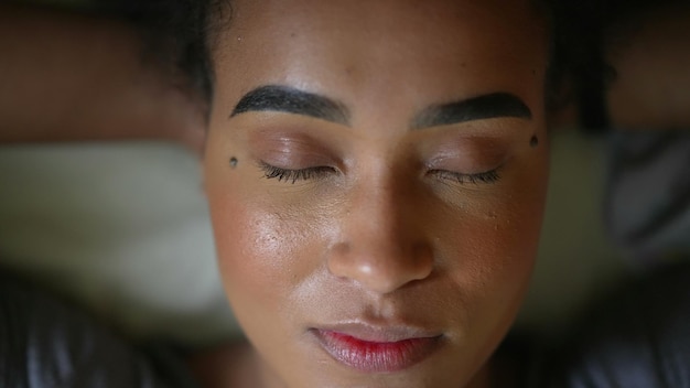 Una mujer africana abriendo los ojos a la cámara sonriendo retrato cara acostada en la cama mirando a la cámara