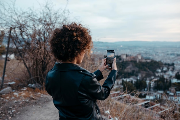 Mujer africana alegre sostiene un teléfono inteligente para tomar una foto del paisaje al atardecer p de alta calidad