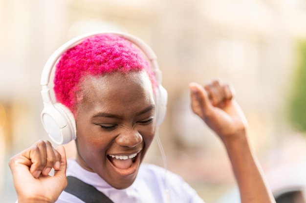 Mujer africana bailando mientras escucha música al aire libre