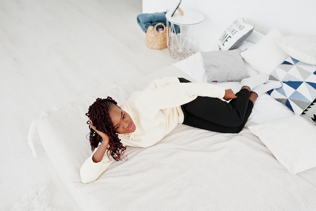 Mujer africana con capucha acostada en la cama en casa.