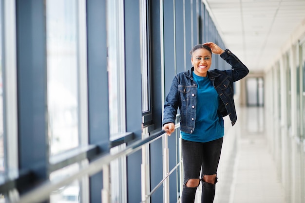 Mujer africana en chaqueta de jeans planteada interior.