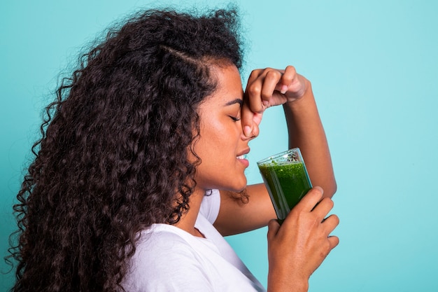 Mujer africana disgustada probando un jugo de verduras con mal sabor