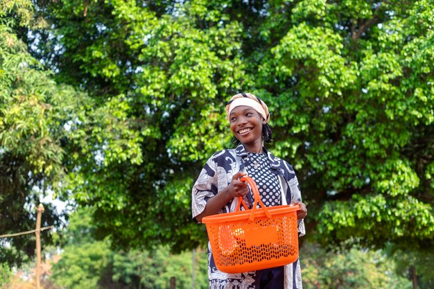 Mujer africana emocionada con una canasta de compras con hojas verdes de fondo