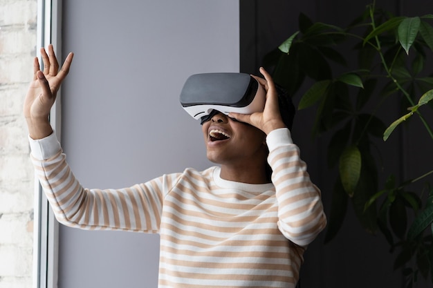 Mujer africana encantada de pasar tiempo libre en realidad virtual mientras se relaja en casa