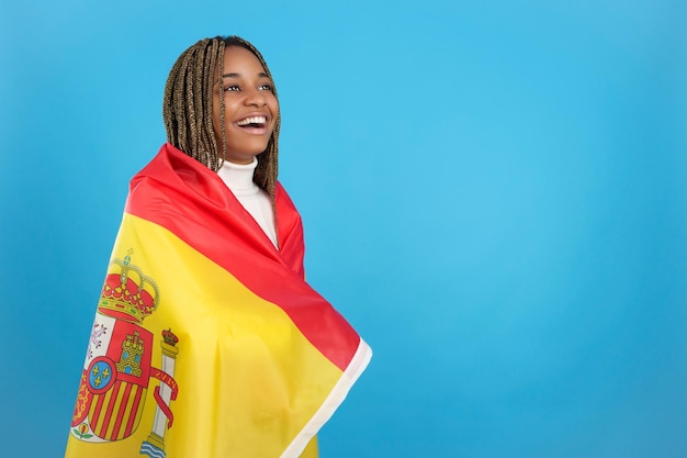 Mujer africana feliz envuelta en una bandera nacional española