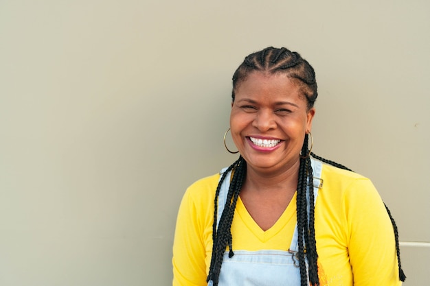 Mujer africana fuera de la ciudad, mirando a la cámara sonriendo.