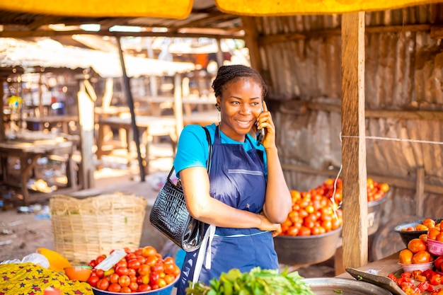 Mujer africana haciendo teléfono en el mercado.