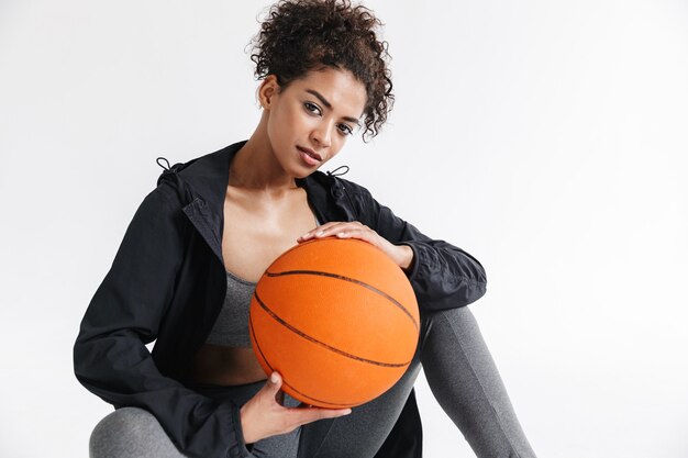 mujer africana hermosa joven deportes asombrosos fitness posando con baloncesto.