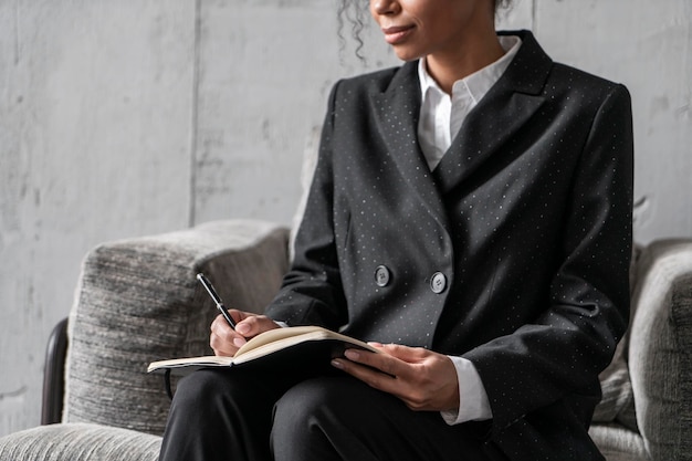 Mujer africana irreconocible escribiendo en un sillón