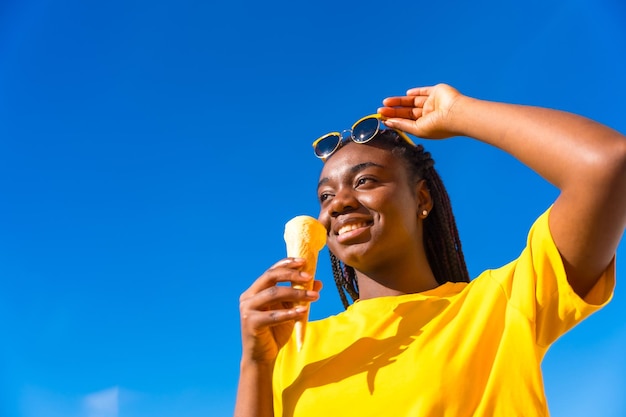 Mujer africana levantando sus gafas de sol mientras come helado