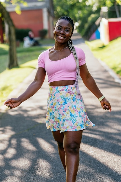 Mujer africana negra muy feliz sonriendo y caminando en un parque público. Estilo de vida de la mujer de moda negra