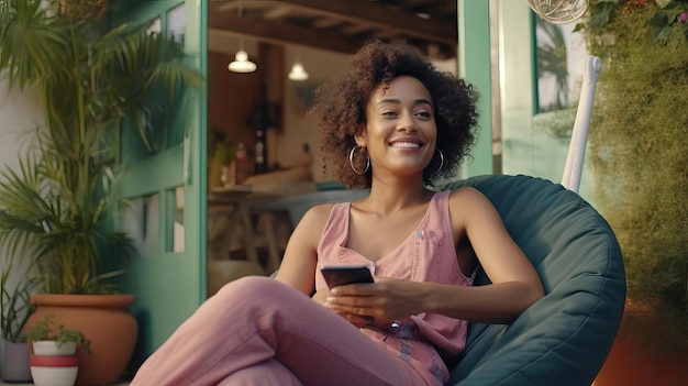 Mujer africana relajándose con el teléfono y con la tableta en una bolsa de frijoles en una casa moderna