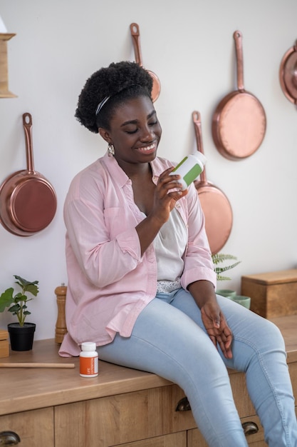 Mujer africana sentada en la mesa con pastillas en las manos