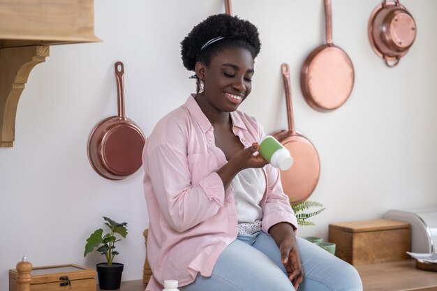 Mujer africana sentada en la mesa con pastillas en las manos