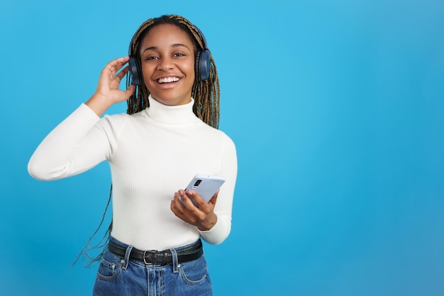 Mujer africana sonriente mirando a la cámara mientras escucha música