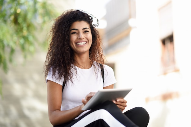 Mujer africana sonriente que usa la tableta digital al aire libre