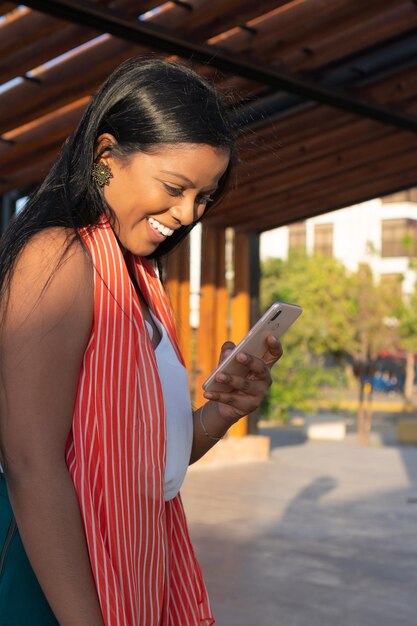 Mujer africana usando celular mientras camina por la calle