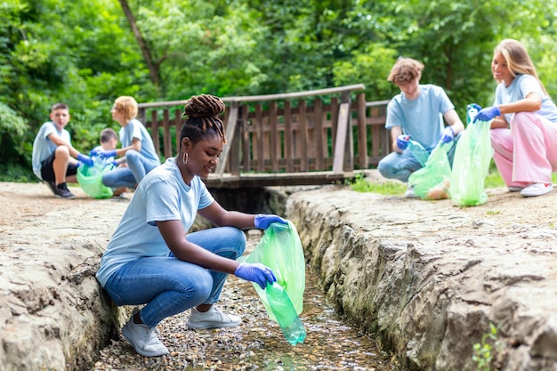 Mujer africana voluntaria recogiendo basura plástica en la costa del río Concepto de entorno de limpieza