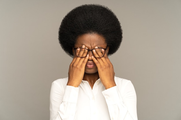 Mujer afro agotada se siente cansada frotándose los ojos después del trabajo, fatiga, exceso de trabajo, computadora