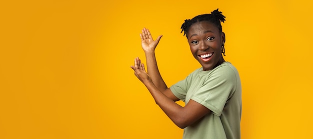 Mujer afro alegre apunta a copiar espacio en estudio amarillo