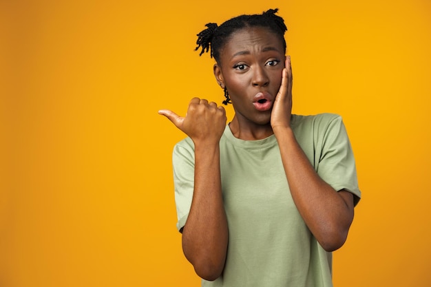 Mujer afro alegre apunta a copiar espacio en estudio amarillo