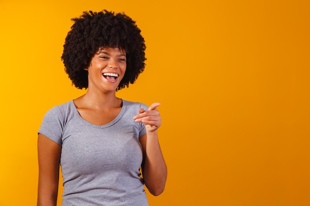 Mujer afro apuntando en amarillo con espacio para el texto