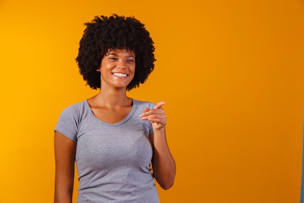 Mujer afro apuntando en amarillo con espacio para el texto