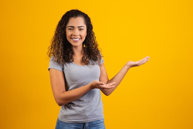 Mujer afro apuntando en fondo amarillo con espacio para el texto