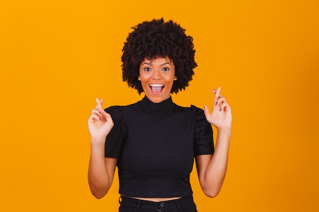 Mujer afro con los dedos cruzados animando la victoria