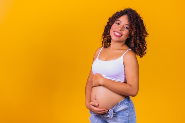 Mujer afro embarazada sobre fondo amarillo