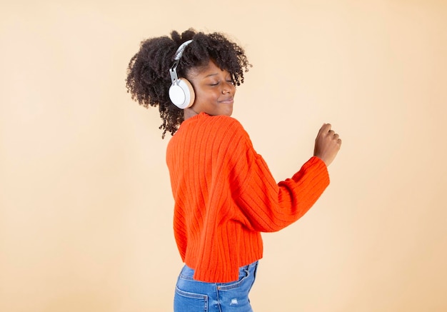 Mujer afro escucha música con auriculares mientras disfruta bailando