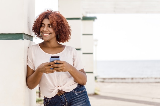 Mujer afro feliz usando un teléfono móvil con espacio de copia. concepto de comunicación y tecnología.