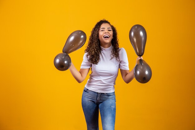 Mujer afro con globos negros celebrando ofertas de cumpleaños. Rebajas del Black Friday