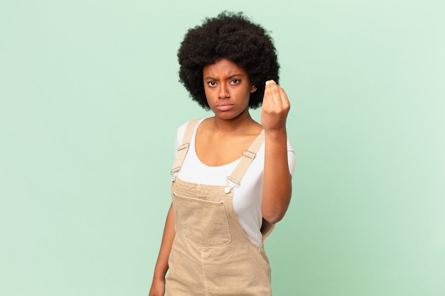 Mujer afro haciendo capice o gesto de dinero, ¡diciéndote que pagues tus deudas! concepto de chef