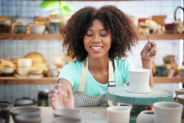 Mujer afro haciendo cerámica en el taller Dando forma a la arcilla húmeda en la rueda de alfarería