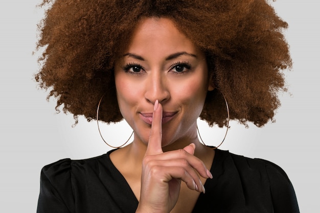 Foto mujer afro haciendo un gesto de silencio, primer plano cara