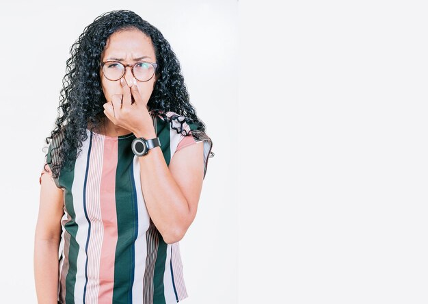 Foto mujer afro joven disgustada cubriendo la nariz mujer con gafas cubriendo la nariz de un mal olor aislada chica afro disgustada sosteniendo su nariz aislada