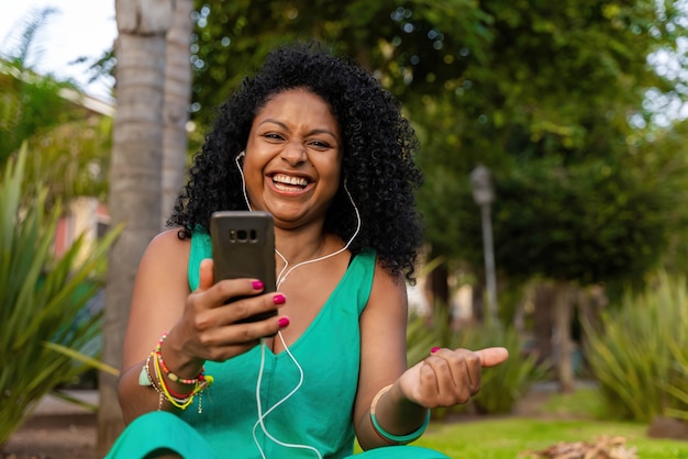 Mujer afro latina con auriculares y móvil