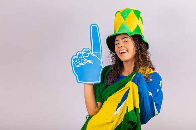 Mujer afro mirando a cámara sosteniendo un guante de fútbol en traje brasileño.