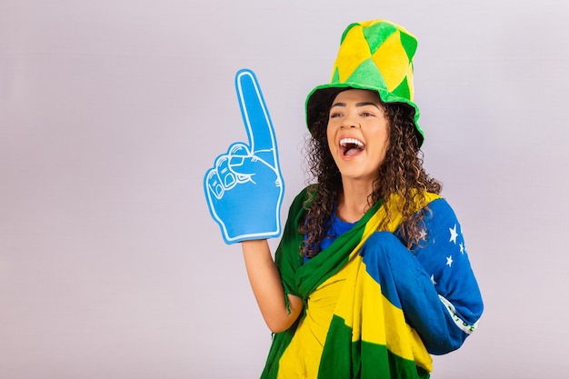 Mujer afro mirando a cámara sosteniendo un guante de fútbol en traje brasileño.