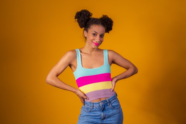 Mujer afro con moño de pelo sobre fondo amarillo sonrisa a la cámara