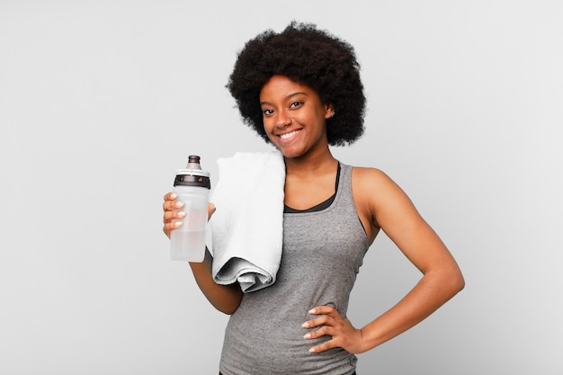 mujer afro negra fitness con una toalla y agua puede